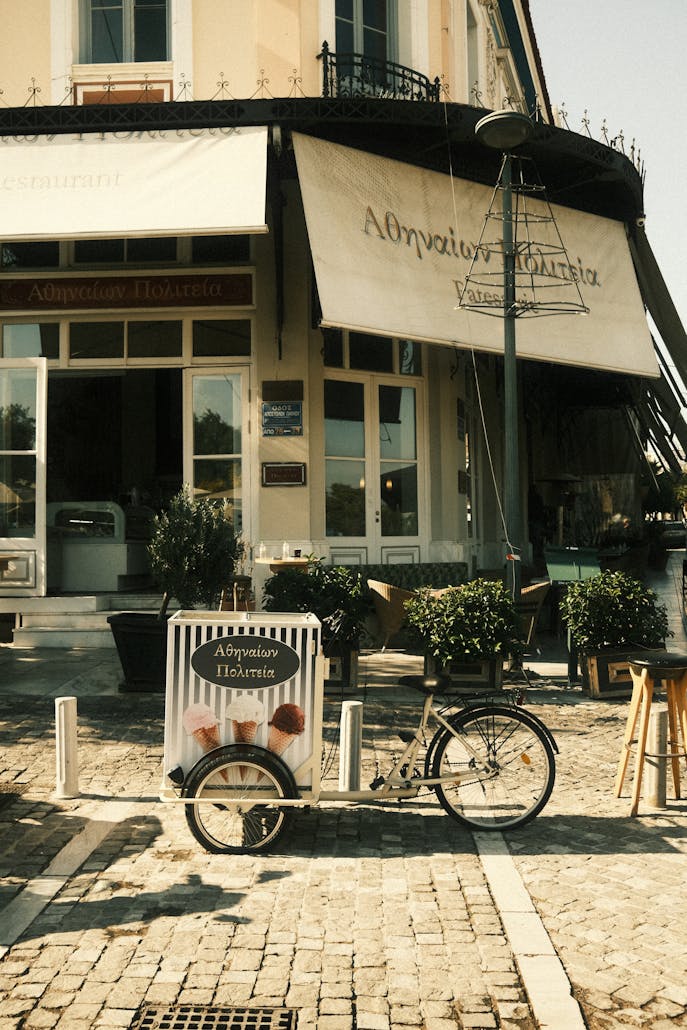 Vintage-style ice cream cart parked on quaint street corner outside a local shop.