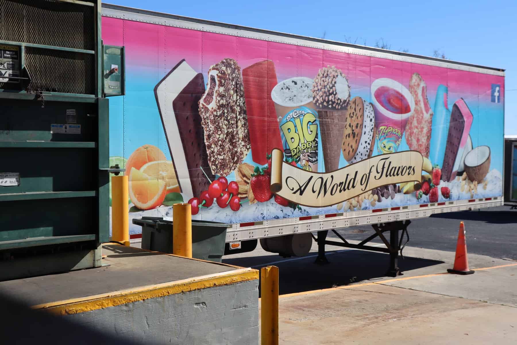 Side of a DeConna semi truck showing the A World of Flavors wrap with ice cream bars, sundae cones, sandwiches, cups and Italian ice